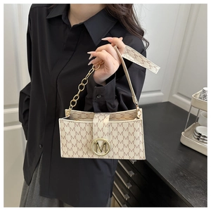 Detail of trendy monogram small square bag with golden M buckle and metal chain strap