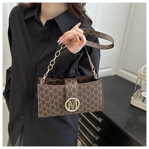 Detail of monogrammed brown crossbody bag featuring golden M logo buckle and chain strap