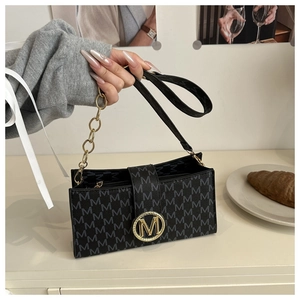 Close-up of printed M pattern and gold metal clasp on a vintage crossbody bag
