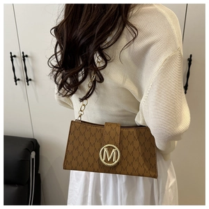 Close-up of brown letter M pattern handbag with golden chain strap and round metal buckle
