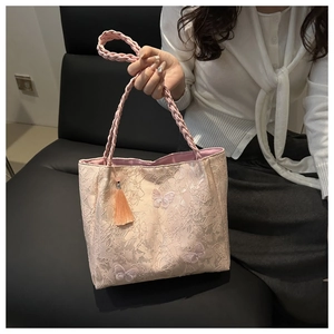 Close-up of pink lace tote bag with floral patterns, butterfly embroidery, and tassels