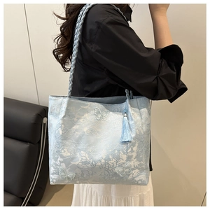 Detail view of light blue tote bag with floral lace embroidery and butterfly applique