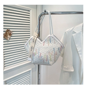 Detail of white quilted tote bag with colorful mountain embroidery and wide branded strap