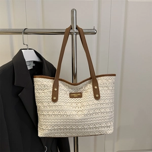 Chic woven lace tote bag with brown leather handles and gold studs for summer 2025