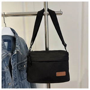 Détail du sac bandoulière en nylon imperméable avec sangle réglable et logo en cuir