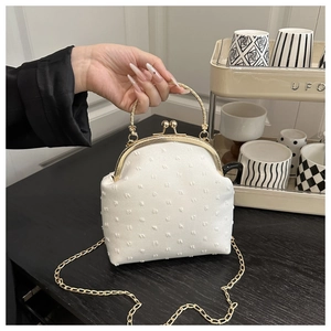 Detail of white jacquard shell bag with textured dots and gold metal handle