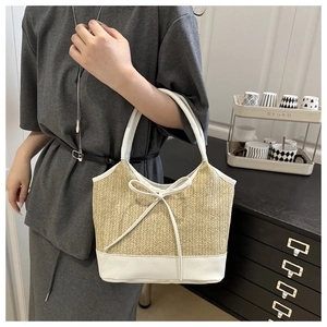 Detail of summer straw shoulder bag with bow knot and contrast leather trim accents