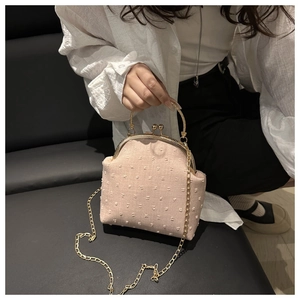 Close-up of pink textured fabric small square bag with metal clasp and gold chain strap