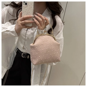Detail of pink vintage clasp bag with polka dot texture and gold chain strap