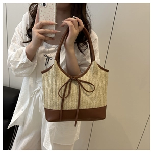 Detail of straw woven bag with brown leather bow and handles shown in a mirror selfie