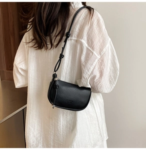 Detail of black lychee grain leather crescent bag with unique knotted strap and silver zipper
