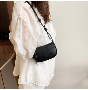 Detail der schwarzen Satteltasche aus genarbtem Leder mit geknotetem Schultergurt am Model