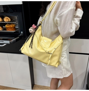 Detail of bright yellow glossy leather bag with drawstring and cute monkey charm