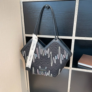 Black canvas tote bag with colorful embroidery and wide webbing strap shown on a cabinet