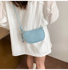 Close-up of light blue saddle bag featuring pebble grain leather and silver zipper detail