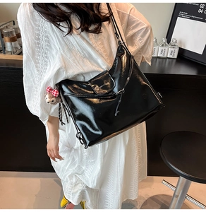Close-up of a glossy black retro tote bag featuring a cute teddy bear charm detail