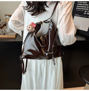 Close-up of a glossy coffee brown shoulder bag featuring a cute plush bear charm