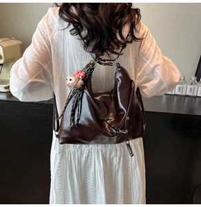 Detail of vintage brown oil wax leather tote bag with cute bear charm and bow accessory