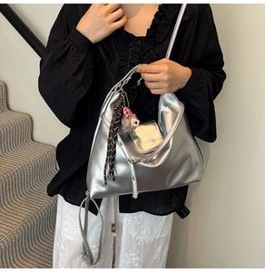 Detail of silver metallic PU leather tote bag with brand logo and cute plush charm