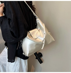 Detail of silver metallic tote bag featuring wide adjustable strap with metal eyelets