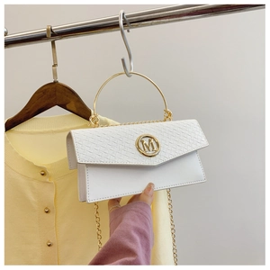 Detail of white mini bag with crocodile texture, gold M logo and circular metal handle