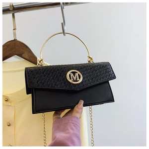 Detail of black woven flap handbag with golden M logo and metal chain shoulder strap