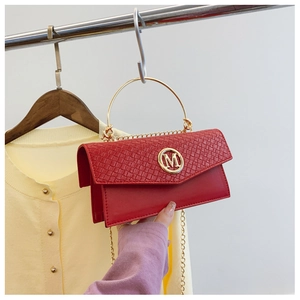 Macro shot of red textured crossbody bag with gold M-logo and metallic handle