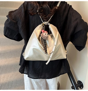 Detailed shot of metallic silver tote bag with plush charm and adjustable strap