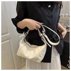 Detail einer cremeweißen glänzenden Handtasche mit Silberreißverschluss und Schultergurt