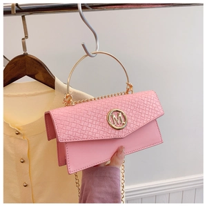 Detail of pink woven leather handbag with gold M logo and round metal handle