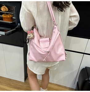 Detail of pink patent leather tote bag with plush bear charm in a modern kitchen setting