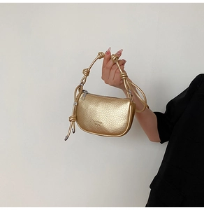 Details der goldenen halbmondförmigen Satteltasche mit Litschi-Struktur und Knotengriff