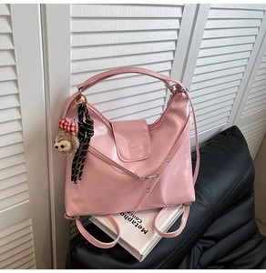 Detailed shot of pink glossy leather tote bag featuring plush pendant and striped ribbon