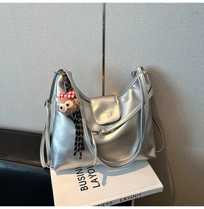Detail of silver metallic leather tote bag with magnetic flap closure and plush bear charm