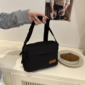 Sac bandoulière noir en nylon imperméable avec plusieurs compartiments zippés