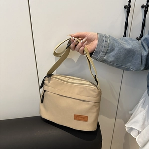 Sac bandoulière en nylon beige avec trois compartiments zippés et sangle réglable