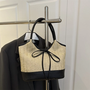 Straw tote bag with black leather trim and bow knot detail on a fashion background
