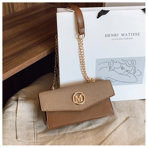 Detalle de bolso caja vintage con solapa de lona beige y herraje dorado con logo M