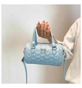 Detail of light blue boston bag with heart quilting and silver bow decoration