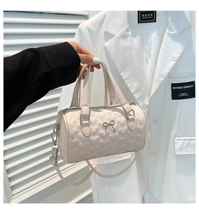 Detail of cream Boston bag with heart embossed texture and silver bow accent