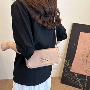 Detail of light pink crossbody bag featuring a golden bow buckle and quilted stitching