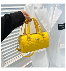 Detail of yellow heart-quilted pillow bag with silver bow accent and adjustable strap
