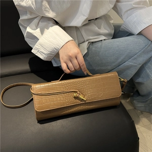 Brown crocodile-embossed baguette handbag with golden knot clasp shown on model