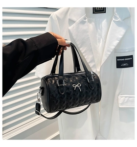 Close-up of black heart quilted Boston bag with silver bow accent and adjustable strap