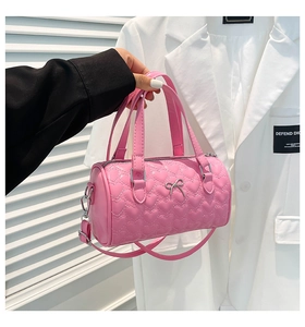 Close-up of pink Boston bag featuring heart quilted texture and metal bow detail