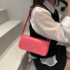 Pink PU leather underarm bag featuring a metallic gold bow and knot strap detail