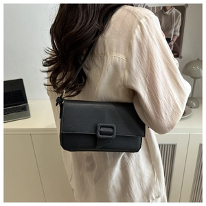 Detail of minimalist black lychee texture leather shoulder bag with buckle on a model