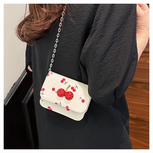 Détail d'un mini sac blanc avec imprimés cerises et breloque en cristal sur mannequin
