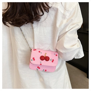 Vue détaillée du sac bandoulière rose à motif cerises avec boucle en strass sur modèle