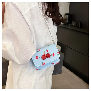 Détail du mini sac bleu clair à imprimé cerises avec boucle en cristal et chaînette